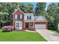 Charming two-story brick home featuring a bay window, manicured lawn, and an attached two-car garage at 101 Creekside Dr, Fort Mill, SC 29715