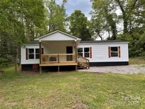 Charming single-story home with a welcoming porch and wood accents, nestled among mature trees in a serene setting at 1016 Old Thompson Ave, Lancaster, SC 29720