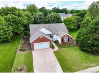 Aerial view of a charming brick and white home with well-manicured lawn and mature trees at 11332 Ridge Oak Dr, Charlotte, NC 28273