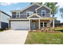 Charming two-story home with a brick and gray siding exterior, a two-car garage and a well-manicured lawn at 119 Obadiah Ct, Mooresville, NC 28115