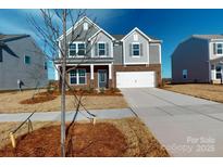 Charming two-story home with gray siding, brick accents, and a two-car garage under a bright blue sky at 1817 Augustine St, Monroe, NC 28112