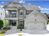 Beautiful two-story home with a covered porch, balcony, attached garage, and manicured landscaping at 2015 Knocktree Dr, Indian Trail, NC 28079