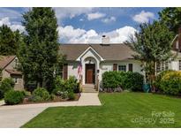 Charming one-story home with an American flag, lush landscaping, a stone chimney, and a well-manicured lawn at 2124 Chatham Ave, Charlotte, NC 28205