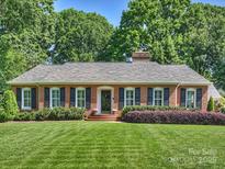Charming brick home featuring manicured lawn, mature trees, and neatly trimmed shrubs at 3620 Champaign St, Charlotte, NC 28210