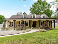 Charming single-story home featuring a welcoming front porch, dormer windows, and lush landscaping at 4711 Truscott Rd, Charlotte, NC 28226