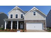 Charming two-story home featuring stone accents, a welcoming front porch, and a pristine two-car garage at 905 Barker St, Monroe, NC 28112