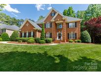 Stately brick home featuring manicured lawn, mature trees, and classic architectural details at 905 Patricians Ln, Monroe, NC 28110