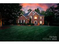 A brick two-story home features a lush green lawn, mature trees, and traditional architectural details at 905 Patricians Ln, Monroe, NC 28110