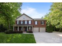 Charming two-story red brick home featuring a covered front porch, attached two-car garage, and well-manicured lawn at 1108 Longwood Ct, Matthews, NC 28104