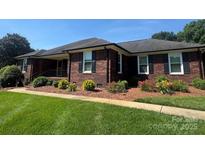 Charming brick ranch-style home with a well-manicured lawn and mature landscaping at 6339 River Front Dr, Harrisburg, NC 28075