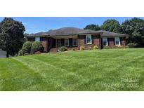 Charming brick home with lush green lawn and mature trees on a sunny day at 6339 River Front Dr, Harrisburg, NC 28075