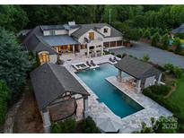 Stunning backyard oasis with a luxurious pool, spa, outdoor kitchen, and multiple lounge areas at 8300 Fairview Rd, Charlotte, NC 28226