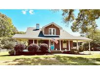 Charming brick home with a welcoming front porch, American flag, and well-maintained landscaping at 1105 S Point Rd, Belmont, NC 28012