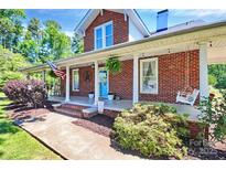 Charming brick home featuring a spacious front porch with white columns and inviting porch swing at 1105 S Point Rd, Belmont, NC 28012