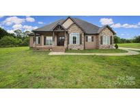 Charming stone and siding home with a covered front porch and well-manicured lawn at 1166 Rocky River Rd, Lancaster, SC 29720