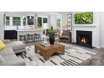 Open-concept living room with modern furnishings, a fireplace, and a spacious kitchen island at 12305 Gambrell Dr, Charlotte, NC 28278