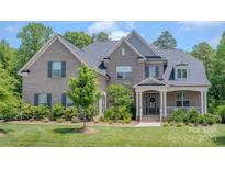 Beautiful two-story home with a brick exterior, professionally landscaped yard, and inviting front porch at 1445 Cherry Laurel Dr, Waxhaw, NC 28173