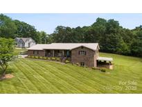 Beautiful brick home with a metal roof, covered carport, and a well-manicured lawn at 1512 Mount Ulla Hwy, Mooresville, NC 28115