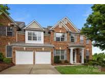 Charming brick home featuring a two-car garage, manicured lawn, and traditional architectural details at 15215 Arleta Cir, Charlotte, NC 28277