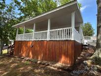 Charming exterior view showcasing a covered porch with white railings and wood-finished siding at 164 Dogwood Cir, New London, NC 28127