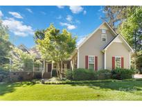 Charming home with lush lawn, mature tree, neutral siding, red shutters and covered entry at 2923 Meadow Creek Ln, Monroe, NC 28110
