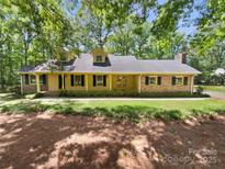 Charming yellow brick and siding home with dormers, surrounded by mature trees and a well-maintained lawn at 3203 Oakdale Dr, Monroe, NC 28110