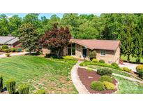 Beautifully landscaped home with mature trees, stone facade, and a well-maintained lawn at 3520 4Th Street Nw Blvd, Hickory, NC 28601