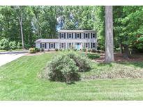 Charming two-story home featuring a well-manicured lawn, mature trees, and a welcoming blue front door at 417 Florence Cir, Statesville, NC 28625