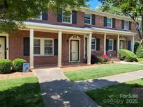 Charming brick townhouse featuring a covered front porch, black shutters, and manicured lawn at 623 S New Hope Rd # 9, Gastonia, NC 28054