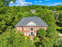 Stunning brick home featuring mature trees, a well-manicured lawn and impeccable landscaping at 9311 St Barts Ln, Huntersville, NC 28078