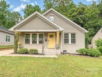 Charming bungalow-style house featuring a yellow front door and a well-manicured lawn at 2323 Arden St, Charlotte, NC 28206