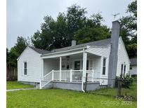 Charming home featuring a covered front porch, white siding, and a painted brick chimney at 247 E Cabarrus Ave, Concord, NC 28025