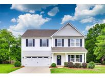 Charming two-story home featuring a well-manicured lawn and a two-car garage and beautiful blue skies at 5305 Friendly Baptist Church Rd, Indian Trail, NC 28079