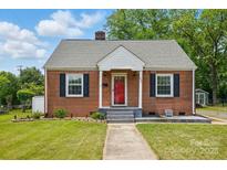 A brick house featuring black window shutters, a red front door, and a well-manicured lawn at 604 Meadowbrook Rd, Kings Mountain, NC 28086