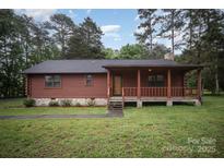 Charming log cabin with stone accents and a cozy front porch nestled among mature trees at 8464 Robinson Church Rd, Charlotte, NC 28215