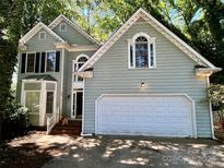 Charming two-story home with a light green exterior, arched windows and a two-car garage, surrounded by lush greenery at 9907 Furlong Trl, Charlotte, NC 28269