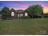Charming brick home with manicured lawn and mature trees set against a vibrant twilight sky at 1021 Mallard Landing Dr, Monroe, NC 28110