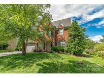 Charming two-story brick home with manicured lawn, mature trees, and a two-car garage at 10418 Goosefoot Nw Ct, Concord, NC 28027