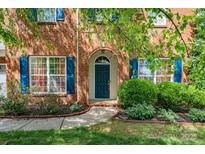 Charming brick home featuring a blue front door, arched entryway, and manicured landscaping at 10418 Goosefoot Nw Ct, Concord, NC 28027