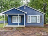 Charming blue home featuring a quaint front porch and freshly painted shutters, nestled among mature trees at 2123 W Sixth Ave, Gastonia, NC 28052