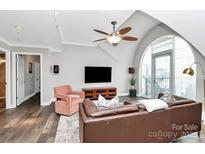 Bright living room with large arched window, ceiling fan, leather sofa, and dark wood flooring at 300 W 5Th St # 644, Charlotte, NC 28202