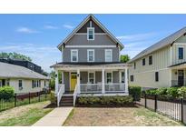 Charming two-story home with a welcoming front porch, yellow door, and beautifully landscaped yard at 423 State St, Charlotte, NC 28208