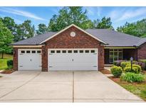 Well-maintained brick home featuring a spacious driveway leading to a three-car garage with white doors at 4860 Sherborne Dr, Harrisburg, NC 28075