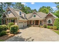 Charming home featuring stone accents, a welcoming front porch, well-manicured landscaping, and a spacious driveway at 104 Whiterock Dr, Mount Holly, NC 28120