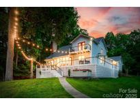 Lake house featuring a spacious deck, hot tub, balcony, and string lights creating a cozy outdoor ambiance at sunset at 18028 Broken Woods Rd, Charlotte, NC 28278