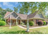 Charming brick home featuring a well-manicured lawn, cozy porch with rocking chairs, and beautiful landscaping at 2020 Olde Towne Dr, Monroe, NC 28110