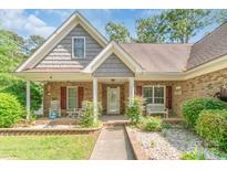 Charming brick home featuring a welcoming front porch, rocking chairs, and well-maintained landscaping at 2020 Olde Towne Dr, Monroe, NC 28110
