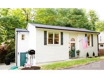 Charming white exterior with green door, flag, and lovely landscaping at 27037 Tidal Way, Tega Cay, SC 29708