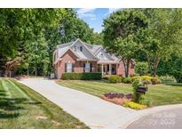 Charming brick home with lush landscaping, manicured lawn, and a long driveway, enveloped by mature trees at 2804 Pulaski Dr, Monroe, NC 28110