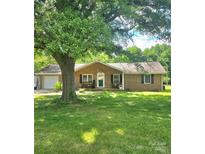 Charming brick home with a well-manicured lawn, mature shade tree, and inviting front porch with benches at 6573 Weldon Nw Cir # 22, Concord, NC 28027